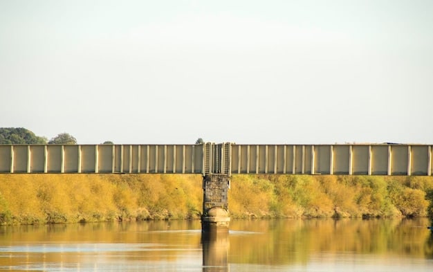 A side-by-side comparison of an old, crumbling bridge and a newly constructed, modern bridge, showcasing the improvements made possible by the Infrastructure Bill.